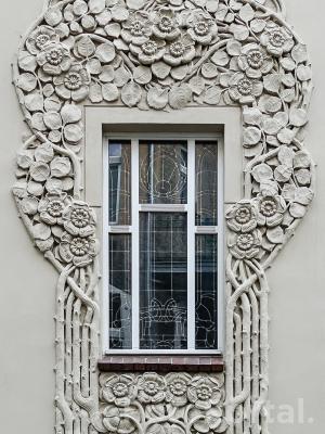 Secesyjne okno z dekoracją roślinną na fasadzie kamienicy w Poznaniu
